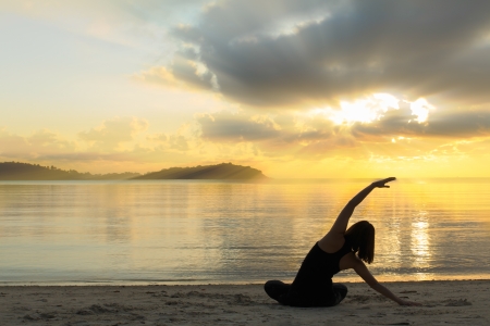 silhouette of a beautiful yoga girl at sunrise on the beachの写真素材