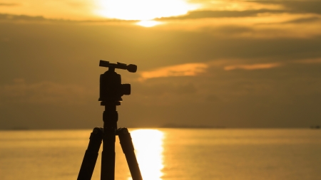 silhouette of a tripod at sunset over sea