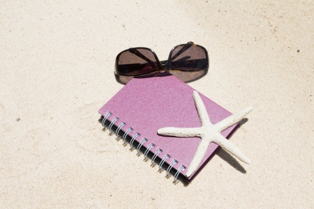 Notebook sunglass and starfish lying on beachの写真素材