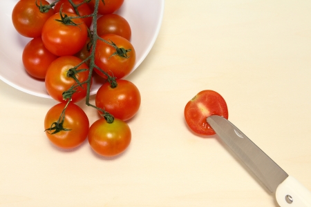 Fresh, ripe cherry tomatoes with knife on wooden board.の写真素材
