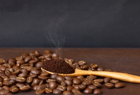 Coffee beans and ground coffee on wooden spoon with grunge backgroundの写真素材