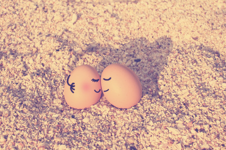 Happy lover eggs sitting on beach with vintage filtered effect