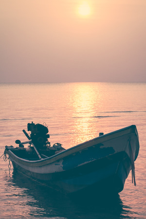Red sunset over sea and sky with fishing boat floating ,vintage filter effectの写真素材