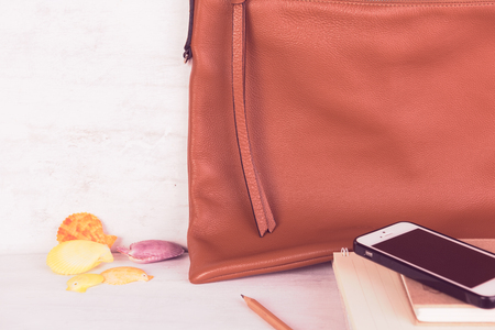 ,mobile phone,notebooks and brown leather bag on grunge white wood backgroundの写真素材