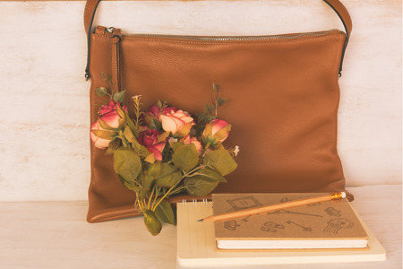 Still life brown leather bag and rose bouquet on white wooden boardの写真素材