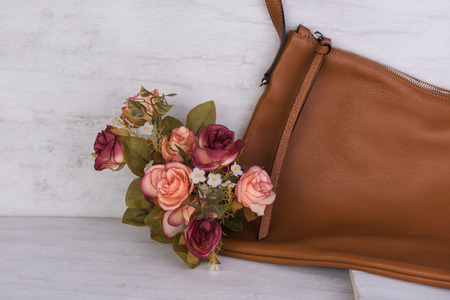 Still life brown leather bag and rose bouquet on white wooden boardの写真素材
