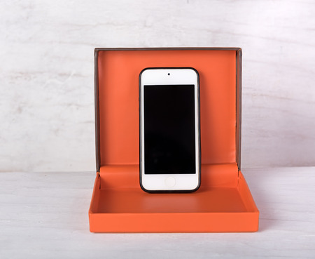 Smartphone in orange gift box on grunge white backgroundの写真素材