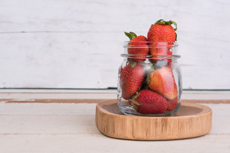 Close up strawberry fruit in glass jar on grunge wood backgroundの写真素材