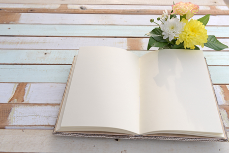 Open notebook and beautiful flowers bouqet on grunge retro wooden backgroundの写真素材