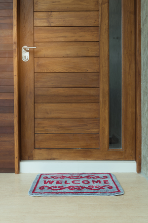 Welcome door mat infront of teak wooden door backgroundの写真素材