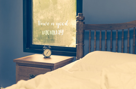 Good Monday text wrote on rain drop window and alarm clock,retro filter in white bedroom,retro...