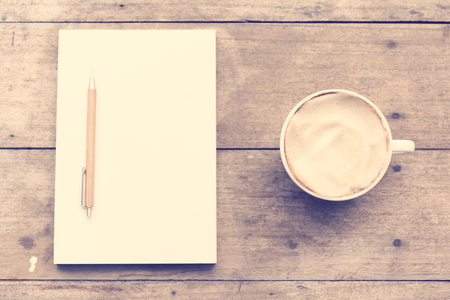 Top view of Coffee cup and notebook on grunge wood background,retro filter imageの写真素材