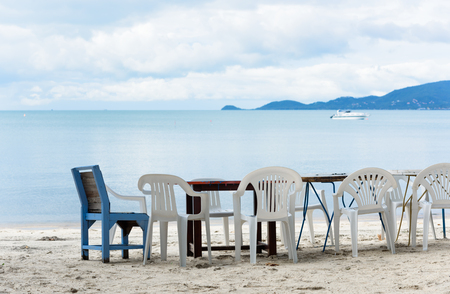 Wooden table and chair set on white beach sand and blue sea in sunny dayの写真素材
