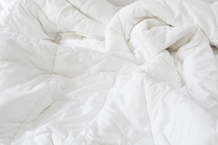 Close up messy white sheet and pillows on bed bedroom interiorの写真素材