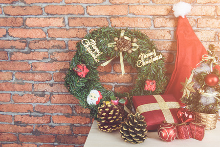 Christmas background with Christmas garland,ball, gift, red hat on wood table and red brick wall background,retro filter effectの写真素材
