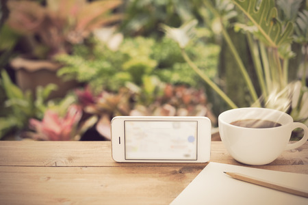 Travel plan,mobile phone,coffee cup,paper and pencil on wooden table in green garden outdoorの写真素材