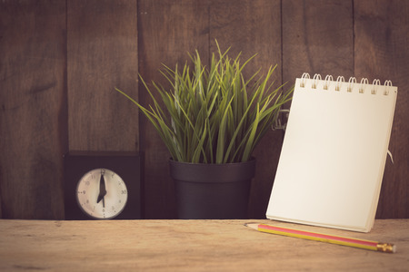 Notebook,alarm clock,flower pot and brown pencil on wood table background,retro effectの写真素材