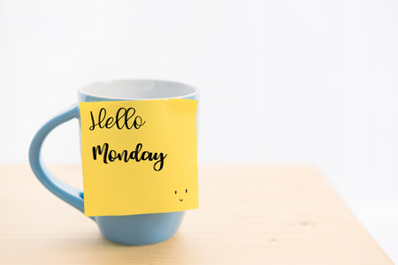 Hello Monday quote wrote on blue coffee cup and post it  on wood table topの写真素材