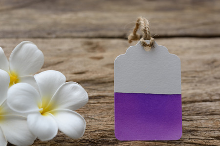 Water color painted on tag label decorate with plumeria flowers on wood tableの写真素材