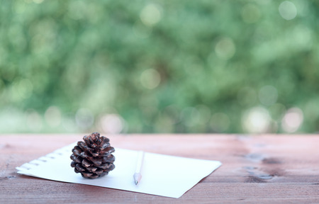 Note paper and brown pencil on wood table background with green blurred backgroundの写真素材