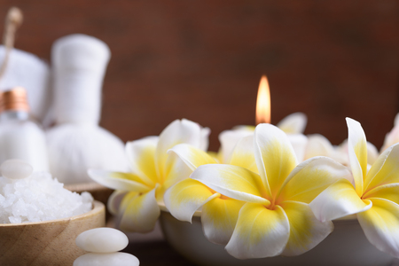 Spa wellness and treatment with essential oils,zen stone,towels,candle,hearbal massage ball and frangipani flowers on wooden table with brick wall backgroundの写真素材