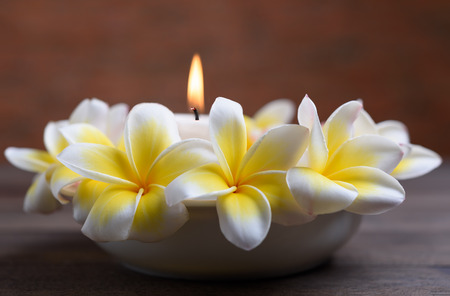 Beautiful Frangipani flowers in white bowl and candle light on wooden background,relaxation and meditation conceptの写真素材