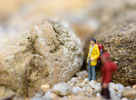 Miniature backpack travelers hiking rock,travel concept