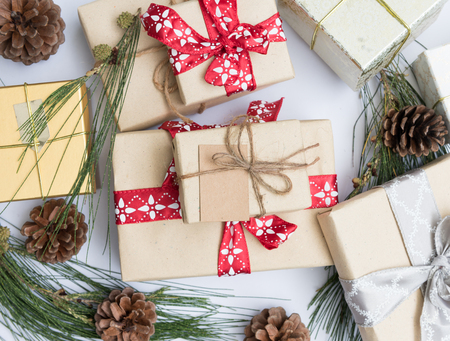 Close up Christmas ornamate brown gift boxes and pine cones fresh green branch on white...