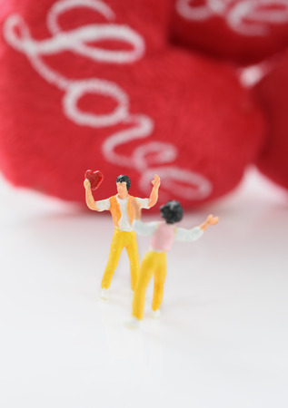 Miniature people,man holding heart icon for woman with love icon background, valentine conceptの写真素材