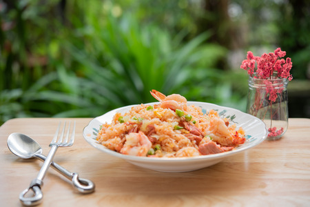 Delicious Thai fried rice with shrimp on wooden table with beauitful vase ,green blurred backgroundの写真素材