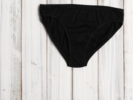 Woman black  panty set on white wooden background, top view