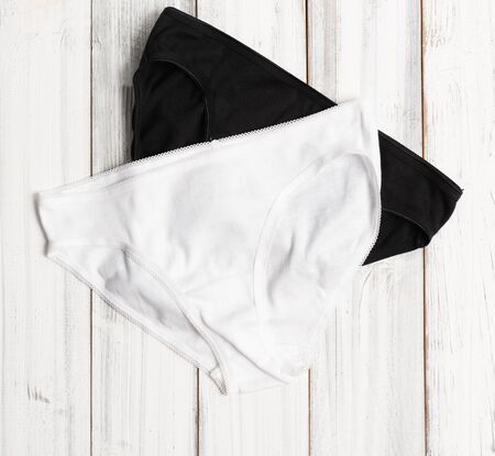 Woman panties set on white wooden background, top view