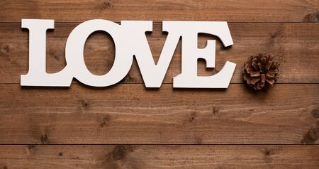 White love  text and pine cone decoration on wooden background