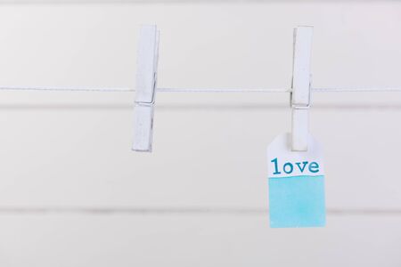 Love label  hang with rope and clothpin over white wood backgroundの写真素材