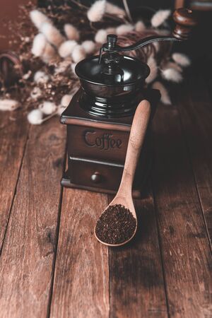Coffee grinder,cooffee ground and coffee beens in burlap  decor with dried flower and blackboard on wood table background in dark toneの写真素材