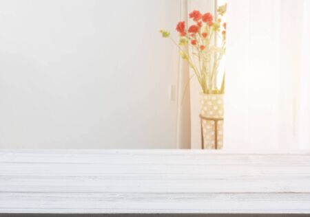 White wood table top with flower pot in living room background with morning light from windowの写真素材