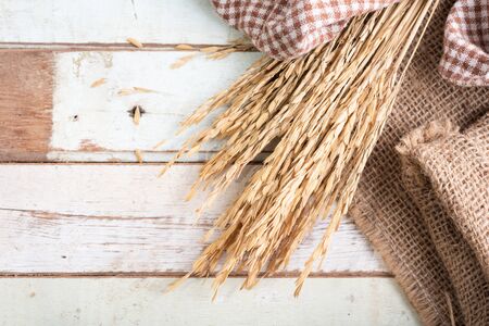 Bouquet dry ears of rice Thai jusmine and burlap or sackcloth on wood table.,top view