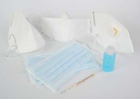 Coronavirus prevention with medical surgical masks, hand sanitizer, alcohol gel and thermometer on white backgroundの写真素材