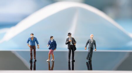 Miniture business people wear mask stand on mobile phone over blue background,due to  Pandemic...