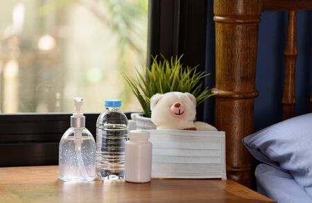 Hand sanitizer,surgical mask,teddy bear and medicine on wood table with green nature background...