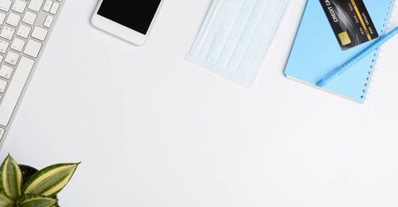Work from home concept due to Covid-19 or Coronavirus with laptop,anote book ,medical mask,credit card and mouse on white background,flat layの写真素材