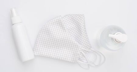 Fabric cloth mask for wearing germ protection  and gel alcohol or hand sanitizer spray bottle for washing hand  to protect from corona virus set on white backgroundの写真素材