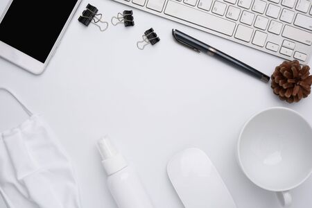 Work from home concept due to Covid-19 or Coronavirus with laptop,antibacterial hand gel, medical mask,coffee cup,pen,pine cone and mouse on white background,flat layの写真素材