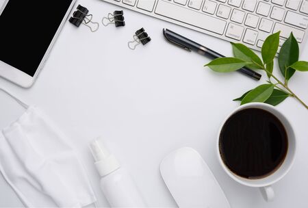 Work from home concept due to Covid-19 or Coronavirus with laptop,antibacterial hand gel, cloth mask,coffee cup,pen,pine cone and  mobile phone on white background,flat layの写真素材