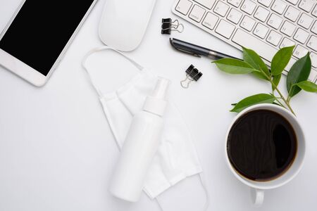 Work from home concept due to Covid-19 or Coronavirus with laptop,antibacterial hand gel, medical mask,hot coffee,and mouse on white background,flat layの写真素材
