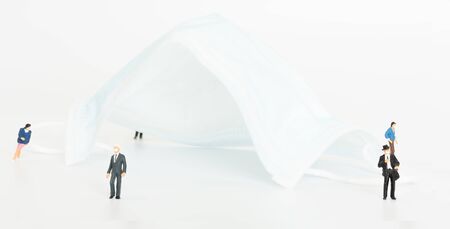 Miniature business people do social distancing  with surgical mask on white background to safe from Coronavirus disease (COVID-19) prevention.の写真素材