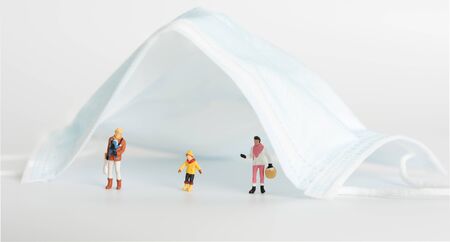 Miniture family people  do social distancing under surgical mas on white background,due to  Pandemic coronavirus(COVID-19)  wear mask can save life conceptual.の写真素材