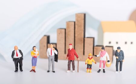 Miniature people family with surgical mask,business graph and house icon on white background due to Coronavirus disease (COVID-19) prevention,people or economyの写真素材
