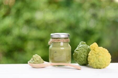 Skin care and spa concept,Thai style with fresh and liquid bergamot  in bottle and wood spoon on white wood table with green nature backgroundの写真素材