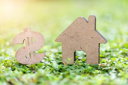 Real estate conceptual with  house and dollar model on fresh green grass and morning sunlightの写真素材
